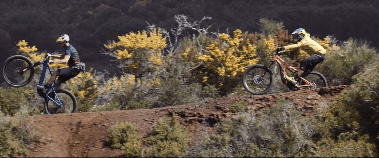 Salto con mountain bike su sentiero sterrato tra cespugli e natura.