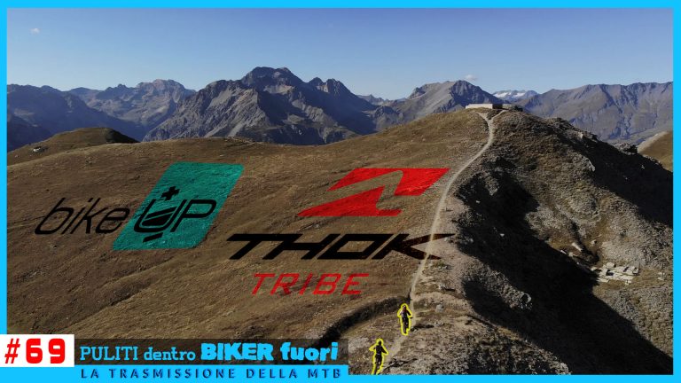 Difficile scatto di mountain bike in un paesaggio montano con logo Bike Up, Thok Tribe e trek. Escursione negli Alpi con ciclisti in azione.