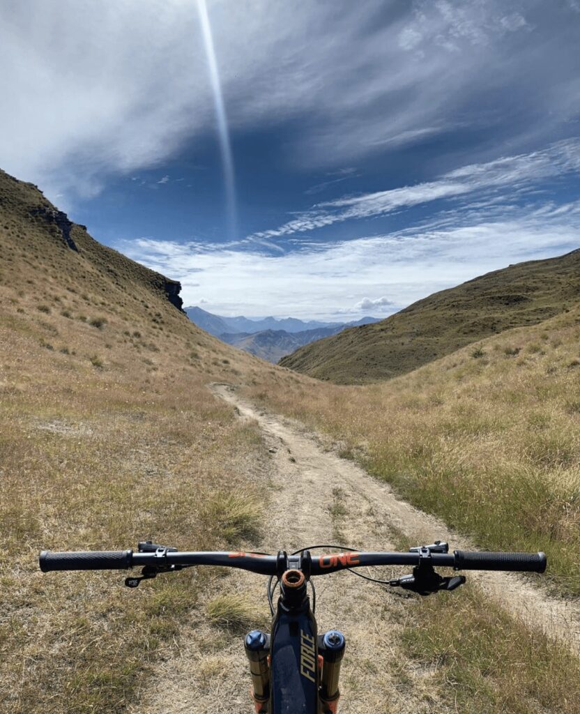 1. Vista di una mountain bike su un sentiero tra le valli montane in un cielo nuvoloso.