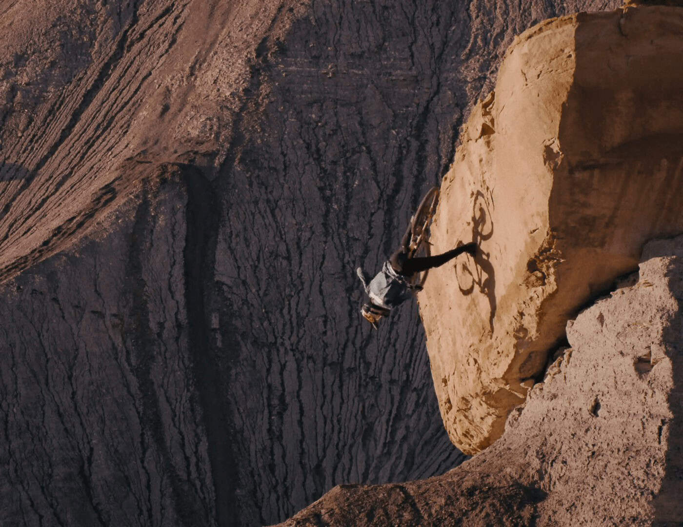 Ciclista in discesa su un sentiero di roccia in un canyon spettacolare.