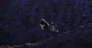 Salto in mountain bike su terreni scoscesi di notte, scena d'azione dinamica e avventurosa.