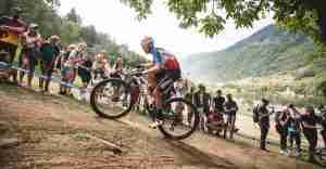 Stunt di mountain bike su un sentiero naturale con pubblico che osserva e riprende.