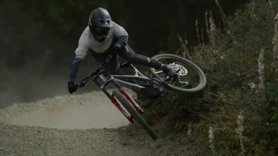 Discesa in mountain bike su sentiero caratterizzato da curve e sterrato, ciclista in azione tra natura e avventura.