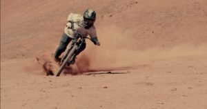 Ciclista in mountain bike su terreno sabbioso, in azione in un deserto.