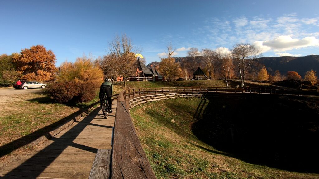 Meraviglioso biker in arrivo nel paesaggio autunnale con alberi colorati e montagne sullo sfondo.