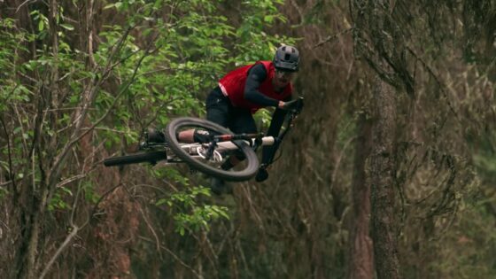 Salto di un ciclista in mountain bike tra gli alberi della foresta, stile avventura e adrenalina.