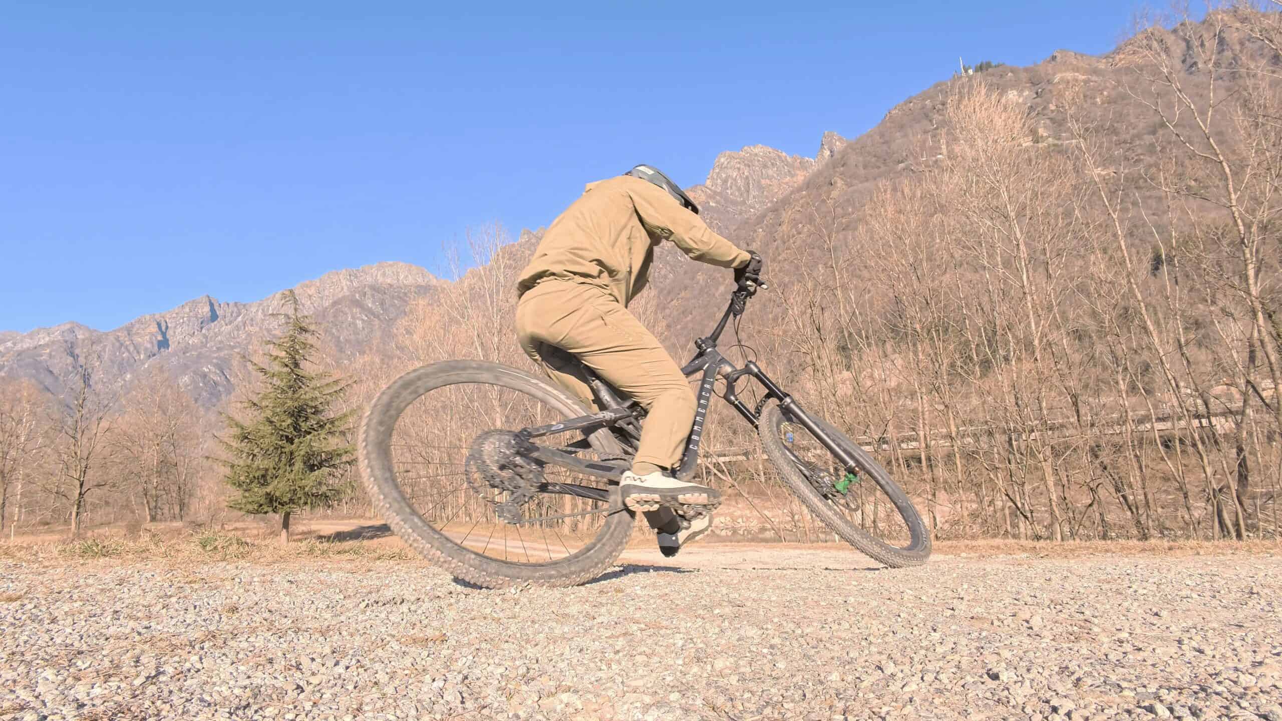 Sfreccia in mountain bike su terreno sterrato con montagne sullo sfondo under cielo sereno.