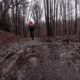 Sentiero di montagna fangoso con ciclista che pedala tra gli alberi spogli in una giornata invernale.