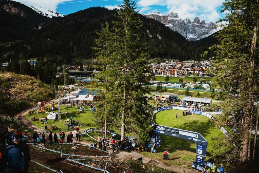 Corsi di mountain bike in un paesaggio alpino con spettatori e un circuito di gara.