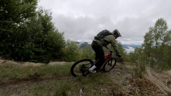 Escursionista su MTB in sentiero di montagna con vista lago, ambiente naturale, cielo nuvoloso, sport all'aperto e avventura.