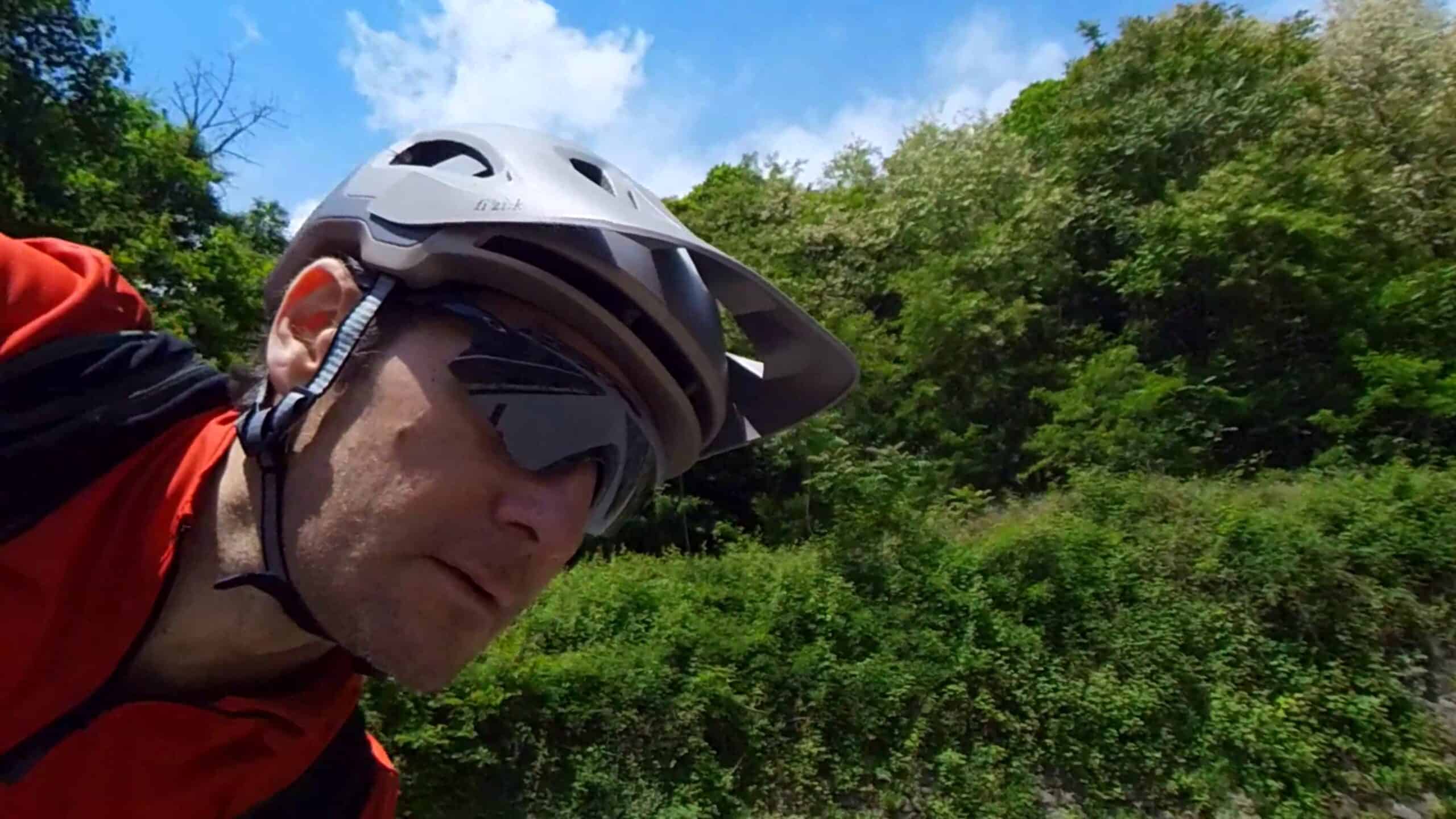 Casco da mountain bike e occhiali protettivi durante un'escursione all'aperto tra la natura.