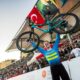 Atleta svedese solleva la bicicletta dopo una vittoria, pubblico entusiasta e arena di gara affollata.