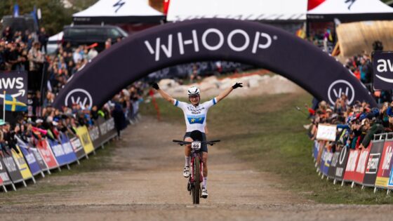 1. Ciclista che festeggia vittoria sotto arco "Whoop" in una gara di mountain bike.