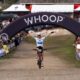 1. Ciclista che festeggia vittoria sotto arco "Whoop" in una gara di mountain bike.