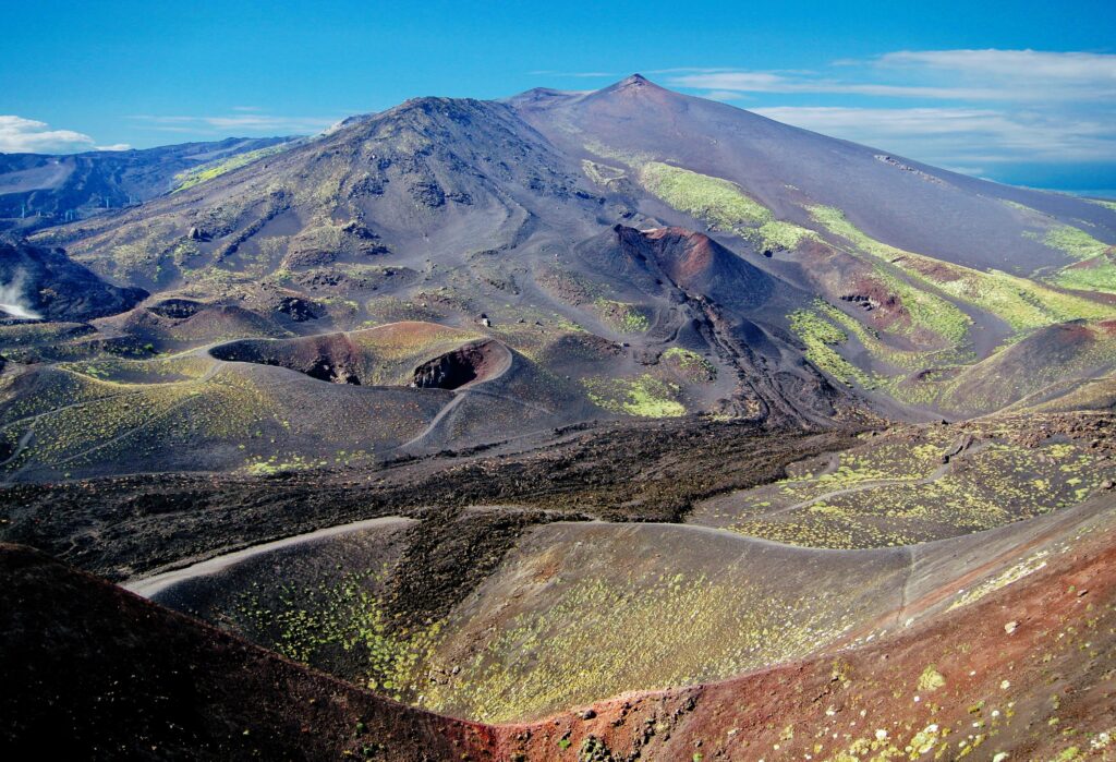 Paesaggio vulcanico con crateri e lave, vista sull'Etna attiva in Sicilia.