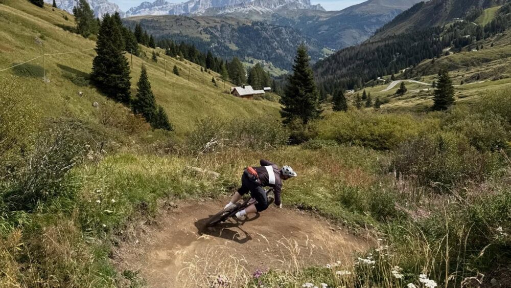 Percorso in mountain bike tra le verdi colline e le montagne innevate sullo sfondo, tra natura e avventura.