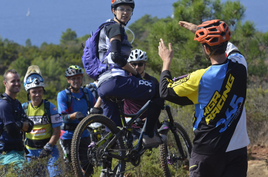 Appassionato di mountain bike che viene assistito da un istruttore durante una gara outdoor. Gruppo di ciclisti su un sentiero di montagna.