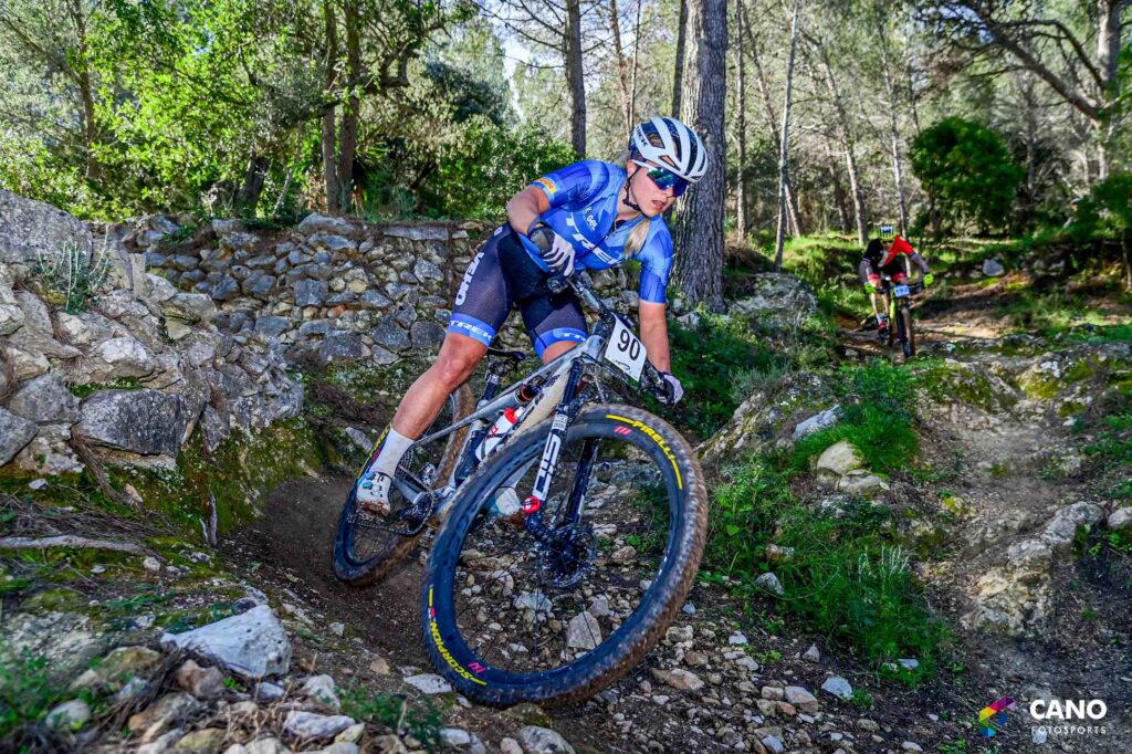 Arrampicata in mountain bike su sentiero roccioso immerso nel bosco.