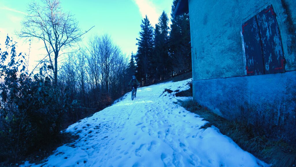 Neve sulla salita delle montagne, ciclista su mountain bike nello sci-alpinismo.