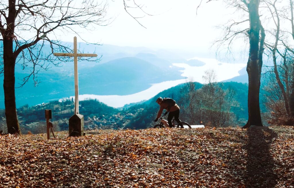 B rider mountain bike in sentiero con vista lago e montagne sullo sfondo, autunno.